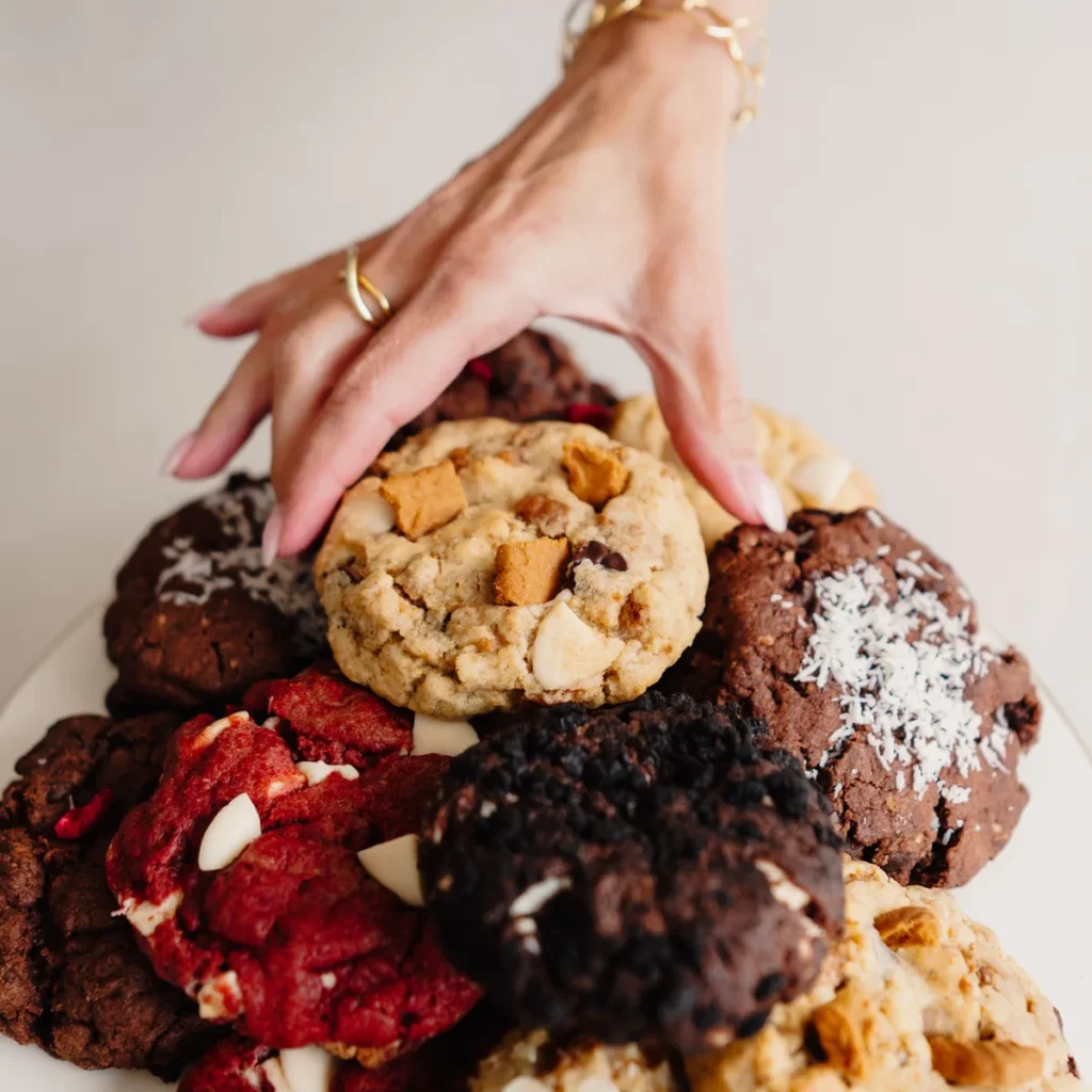 Hand die naar een schaal vol NYC cookies grijpt